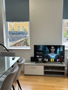 a living room with a tv and two windows at Luxury Flat Near Greenwich Park in London