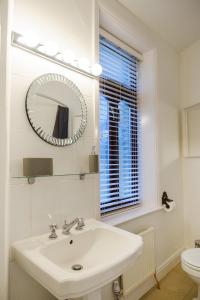 W białej łazience znajduje się umywalka i lustro. w obiekcie Cosy Corner Cottage - Simple2let Serviced Apartments w mieście Halifax