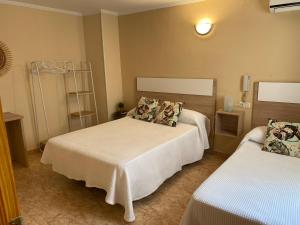 a bedroom with two beds with white sheets at Hotel Valldigna in Tavernes de Valldigna