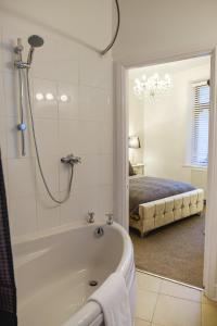 a bathroom with a bath tub and a bedroom at Cosy Corner Cottage - Simple2let Serviced Apartments in Halifax