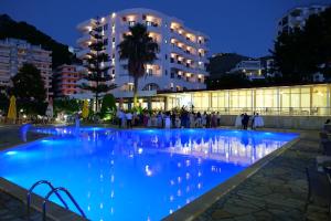a swimming pool at night with a building in the background at Hotel Mediterrane in Sarandë