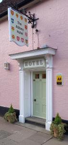 ein rosafarbenes Gebäude mit einer Tür und einem Schild darüber in der Unterkunft The Abbey Hotel & Apartments in Bury Saint Edmunds