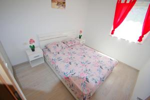 a small bed in a bedroom with red curtains at Holiday apartment Silvija, Loborika in Loborika