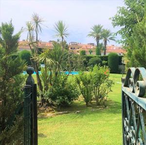 una puerta a un jardín con palmeras y arbustos en Apartamento en Platja Sant Pol S'agaro con pisicina y jardin (playa - centro), en Sant Feliu de Guíxols