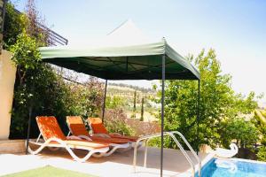 two chairs under an umbrella next to a swimming pool at Green Farm in Jerash