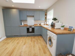 a kitchen with blue cabinets and a washer and dryer at Fir Tree Cottage in Caernarfon