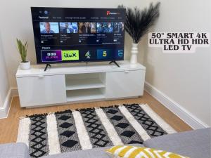 a living room with a tv on a white entertainment center at Brand New! Stunning, Stylish, Cosy Apartment in Centre of Saffron Walden in Saffron Walden