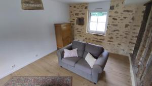 a living room with a couch with two pillows at Petite maison de campagne in La Bazoge