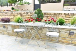 a table and chairs in front of a stone wall at Palio Suites in Paleo Tsifliki
