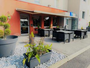 un patio esterno con tavoli, sedie e piante in vaso di ibis budget Noyon a Noyon