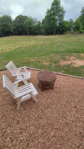 two white chairs and a table on a gravel patio at Petite maison de campagne in La Bazoge