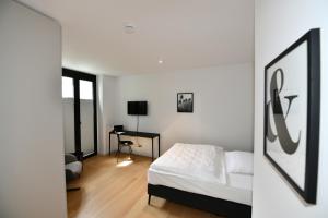 ein weißes Schlafzimmer mit einem Bett und einem Schreibtisch in der Unterkunft Glück Auf Appartements Hillerstraße Köln in Köln