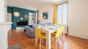 uma sala de estar com uma mesa e cadeiras amarelas em Les Cheminées - Welc'Home em Limoges