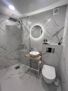 a white bathroom with a toilet and a shower at Treehouse Virš Bedugnės in Jurbarkas