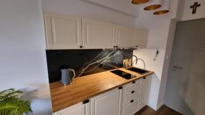 a kitchen with white cabinets and a wooden counter top at Apartament nad zalewem 217 in Serock