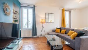 uma sala de estar com um sofá e uma televisão em Les Cheminées - Welc'Home em Limoges