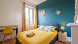 um quarto com uma cama amarela e uma parede azul em Les Cheminées - Welc'Home em Limoges