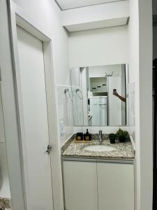 uma casa de banho branca com um lavatório e um espelho em Apartamento 313A Deslumbrante! em Ribeirão Preto
