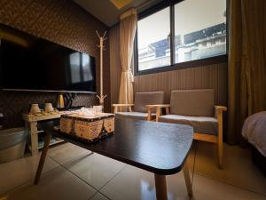 um quarto com uma mesa, um sofá e uma televisão em 一中小窩馨 em Taichung