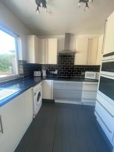 a kitchen with white cabinets and a washer at Cozy bungalow in great location 