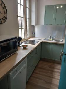 a kitchen with green cabinets and a sink and a microwave at Le naturel d'Amboise in Amboise