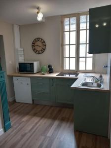 a kitchen with green cabinets and a clock on the wall at Le naturel d'Amboise in Amboise