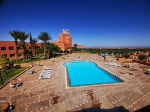 a swimming pool with chairs and a building in the background at Hotel Saghro in Tinerhir