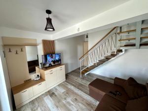 a living room with a staircase and a television at Complex Andris in Murighiol