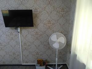 a room with a fan and a tv on a wall at cozy home in Baku