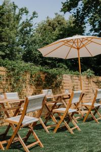 een groep tafels en stoelen met een paraplu bij Hôtel Le Romantica in Pennedepie