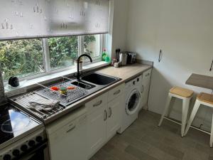 a kitchen with a sink and a washing machine at Spacious one bed apartment in a quiet leafy close. in Barnstaple