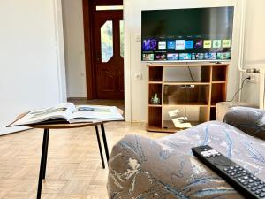 una sala de estar con TV y un libro sobre una mesa en Creekside House K en Mozirje