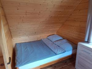 a bed in a wooden room with a wooden wall at 4 Domki u Ewy in Ryn