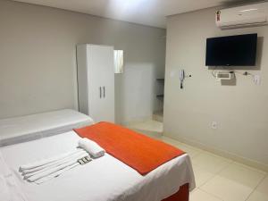 a room with two beds and a flat screen tv at Sobradinho Hotel in Sobradinho