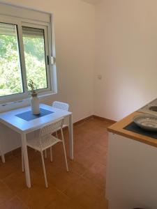 a white table and chairs in a kitchen with a window at Mare Apartments in Bigova