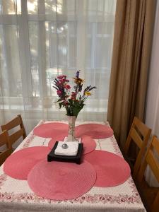 Family Home في بودابست: طاولة مع لوحات حمراء و مزهرية مع الزهور عليها
