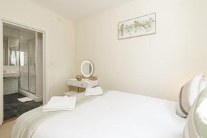 um quarto branco com uma cama e um espelho em Fabulous House near Harrods and the Science Museum em Londres