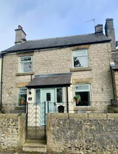 una casa de piedra con una puerta delante de ella en The Beautiful Bobbin - Premium Place to stay - Cottage with views, local walks & pubs, en Tideswell