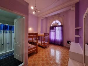 Habitación con paredes moradas, mesa y sillas. en Hostel Estoril en Buenos Aires