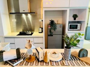 uma cozinha com uma mesa com pratos e plantas em Tropical Style @JB Mosaic(HighFloor)10-13pax 65'TV em Johor Bahru
