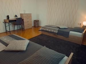 two beds in a room with a desk and a desk at Apartmaji Sofia in Maribor