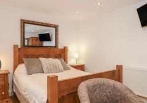a bedroom with a bed with a mirror and a chair at Pine cottage with private hot tub in Upper Hulme