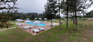 uma vista aérea para uma piscina com cadeiras e guarda-sóis em Къщи за гости Илиеви , Цигов Чарк em Batak