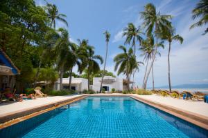 a swimming pool with palm trees and the ocean at Lime N Soda Beachfront Resort in Thong Sala