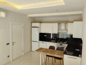 a kitchen with white cabinets and a wooden table at Sea Pearl flat in Avsallar