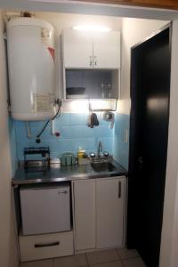 uma pequena cozinha com armários brancos e um lavatório em Loft Mendoza Capital Musica y Fotografia em Mendoza