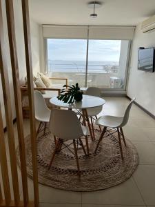 a table and chairs in a living room with a view of the ocean at Monoambiente 509, Dos Orillas in Colonia del Sacramento