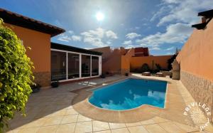 a backyard with a swimming pool and a house at Villa Privilege Sun in Corralejo