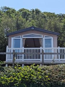 a small house with a porch and a white fence at Panoramic Views Relaxing Caravan Littlesea Haven Weymouth in Weymouth