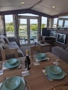 a living room with a table with plates and wine glasses at Panoramic Views Relaxing Caravan Littlesea Haven Weymouth in Weymouth